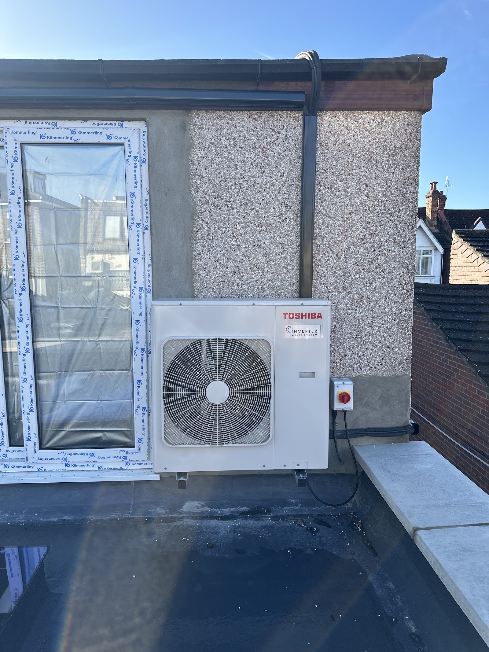 Outdoor unit neatly wall-mounted on a flat roof beside a new window — tidy cabling and a clean, considered position.